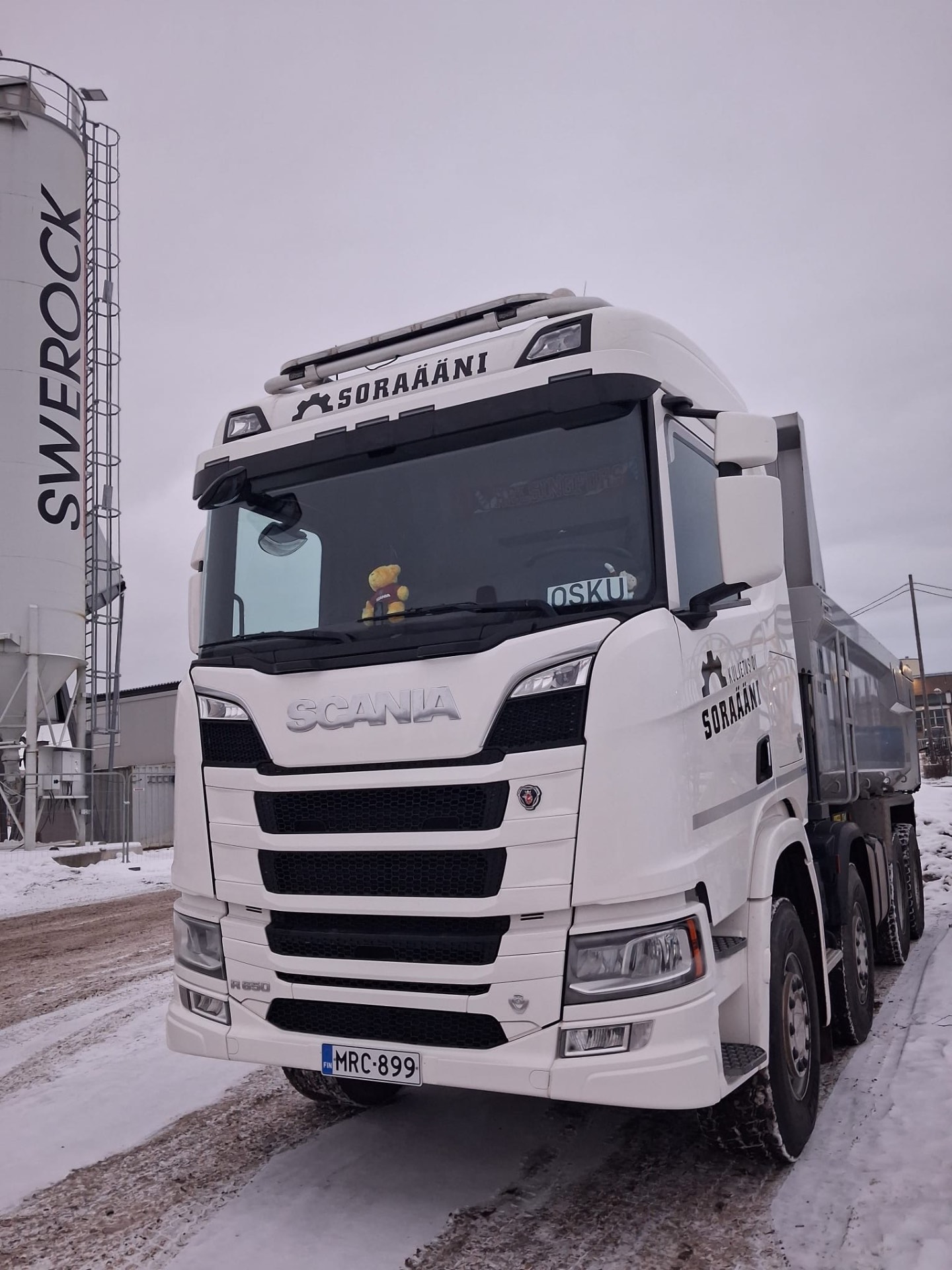 Valkoinen Scania R650 maansiirtoauto Swerock-siilon edessä talvella